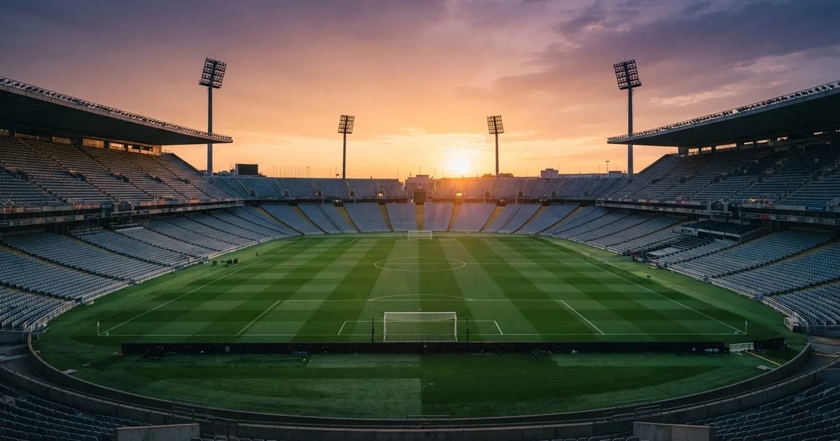 Un estadio de fútbol vacío con torres de iluminación al atardecer