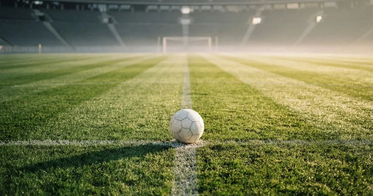 Un balón en el punto central de un campo de césped a la luz de la mañana