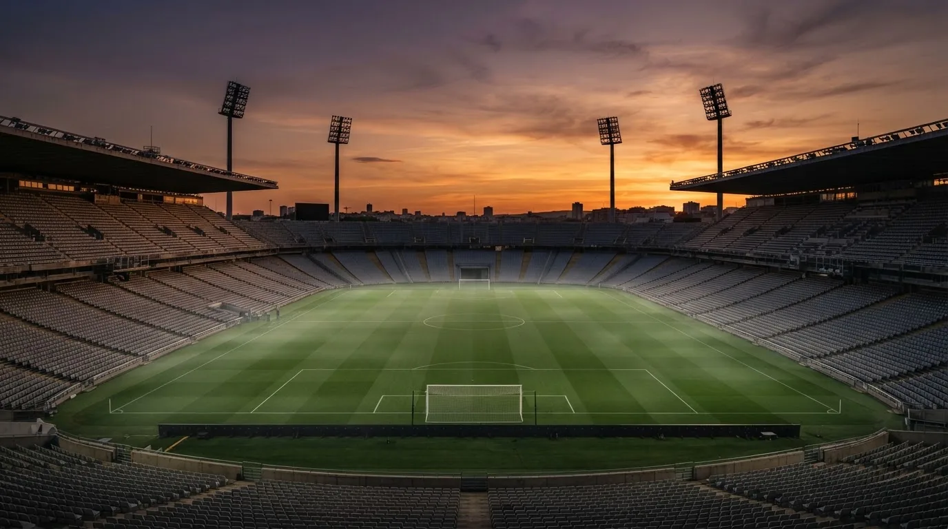 Un estadio de fútbol vacío con torres de iluminación al atardecer