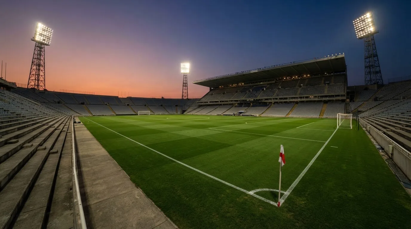 Un estadio de fútbol vacío con torres de iluminación al atardecer