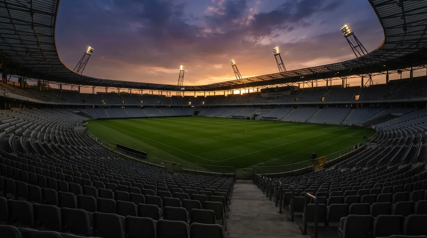 Un estadio de fútbol vacío con torres de iluminación al atardecer