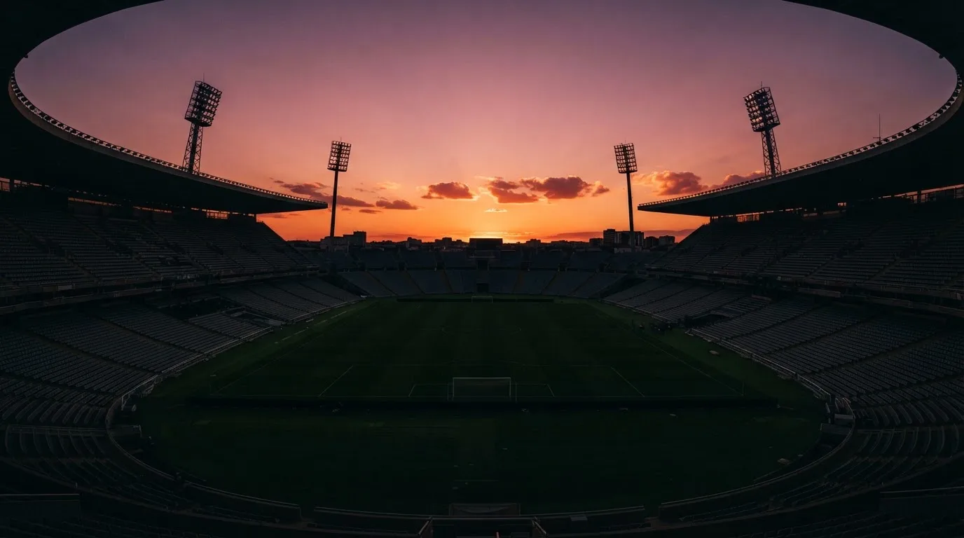 Un estadio de fútbol vacío con torres de iluminación al atardecer