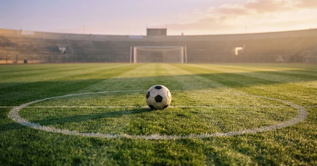 Un balón en el punto central de un campo de césped a la luz de la mañana