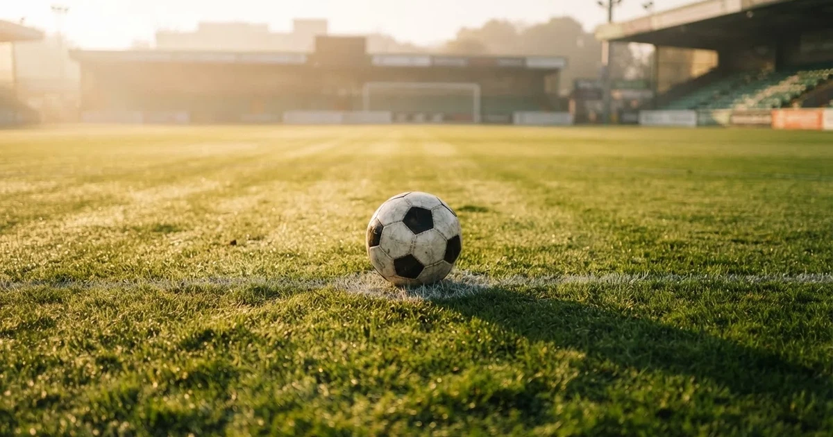 Un balón en el punto central de un campo de césped a la luz de la mañana